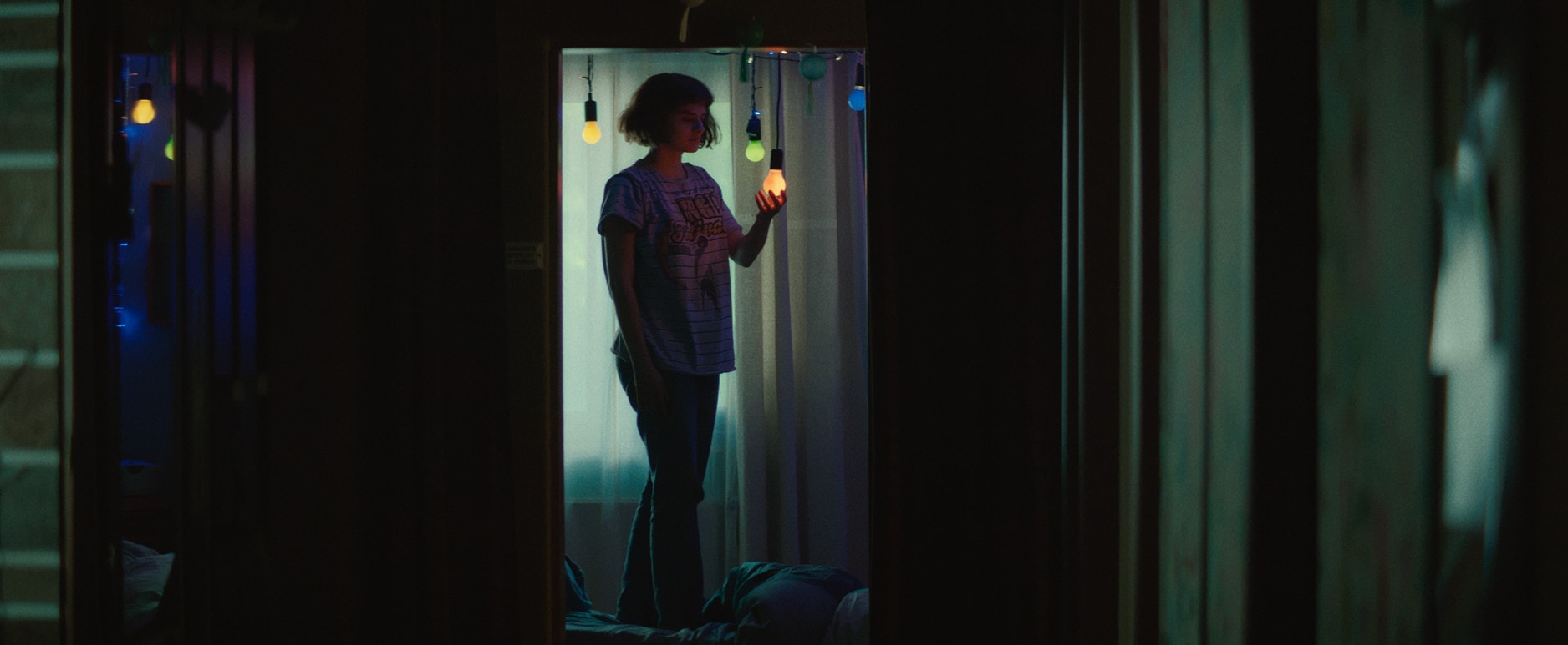 Jeanne (Noémie Merlant) dans sa chambre avec ses bricolages et lumières.