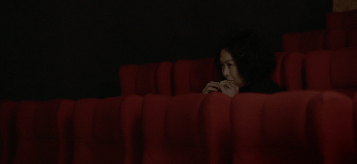 Kim Min-hee assise dans une salle de cinéma dans La Femme qui s'est enfuie