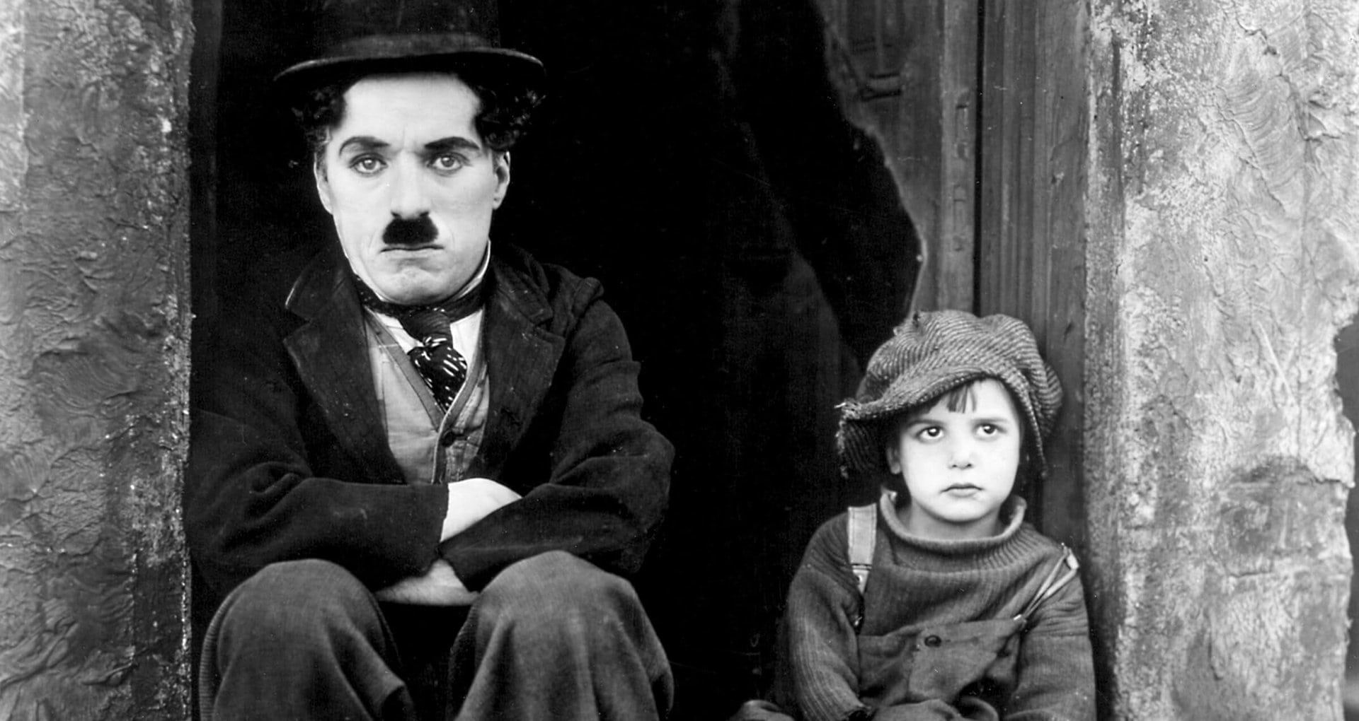 Charlie Chaplin et Jackie Coogan assis dans la rue dans Le Kid