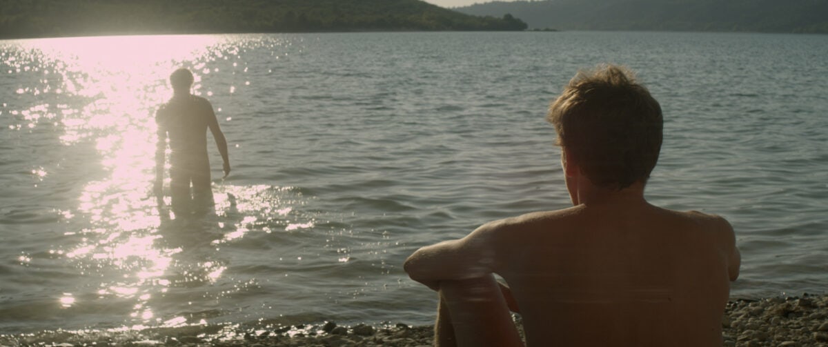 Franck (Pierre Deladonchamps) regarde Michel (Christophe Paou) se baigner dans le lac dans L'Inconnu du lac