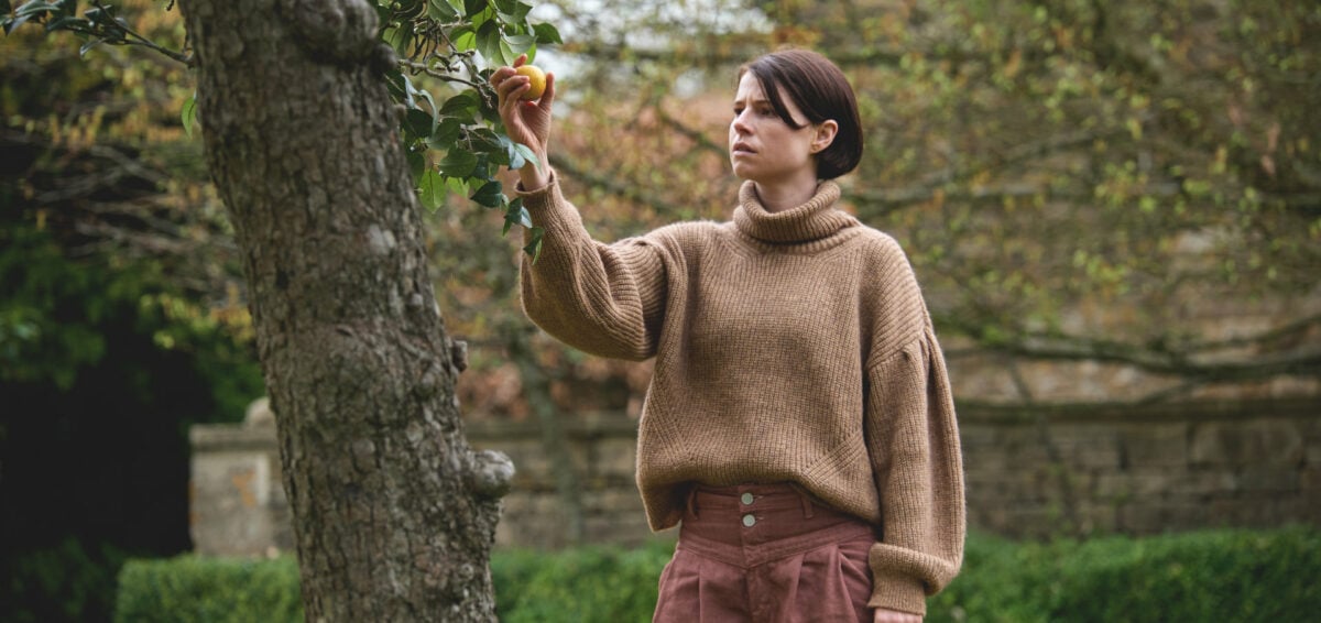 Harper (Jessie Buckley) cueille une pomme dans l'arbre du jardin dans Men