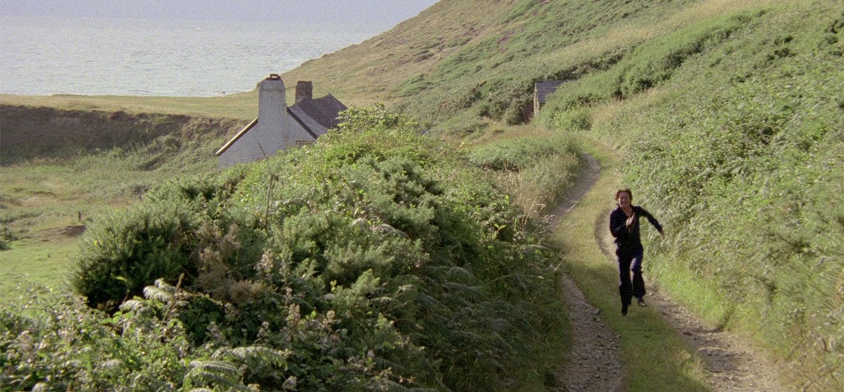 Alan Bates en train de courir sur un chemin de campagne dans Le Cri du sorcier