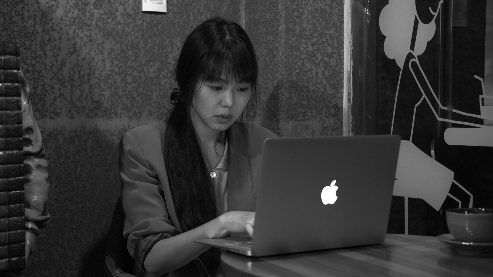 La jeune femme (Kim Min-hee) écrivant sur son ordinateur dans le café de Grass
