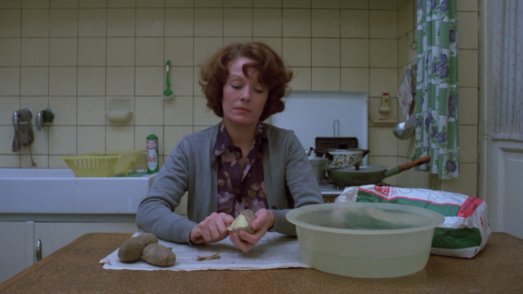 Delphine Seyrig épluche des pommes de terre dans sa cuisine dans Jeanne Dielman