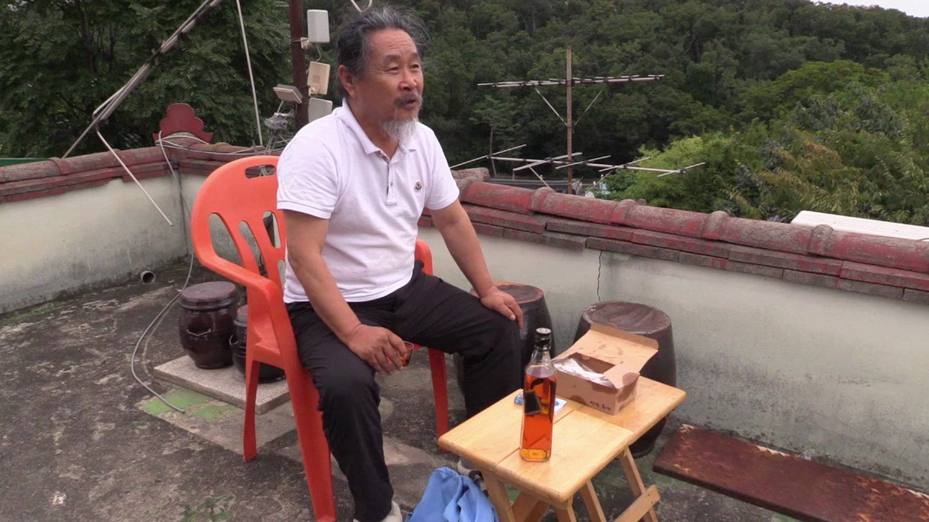 Gi Ju-bong sur la terrasse avec son alcool dans De nos jours...