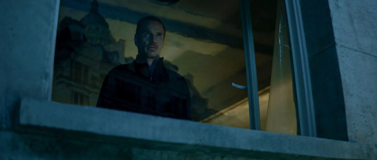 Michael Fassbender à la fenêtre de l'immeuble dans The Killer