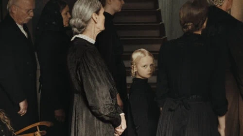 La fille avec sa famille regarde la caméra dans Les Échos du passé de Masha Schilinski