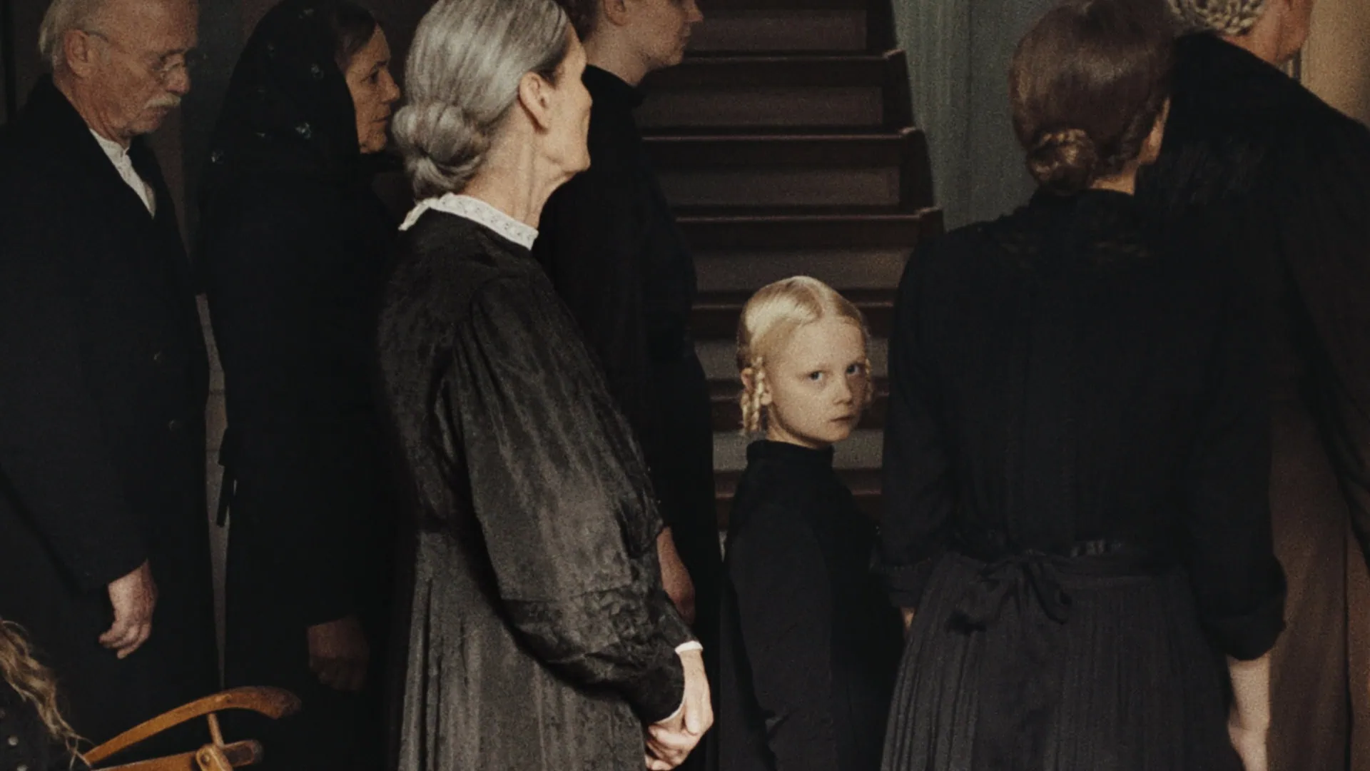 La fille avec sa famille regarde la caméra dans Les Échos du passé de Masha Schilinski