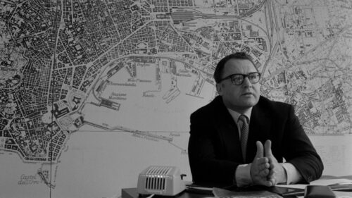 Rod Steiger assis devant une carte de la ville dans Main basse sur la ville de Francesco Rosi