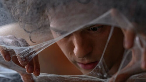 Peter Parker (Tom Holland) écarte la toile d'une araignée dans Spider-Man Brand New Day